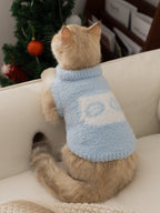 The back of a light blue fuzzy cat sweater worn by a cream-colored cat. The cat is looking away from the camera.