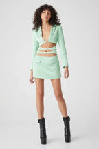 Full length view of a model in a mint green blazer and skirt set.