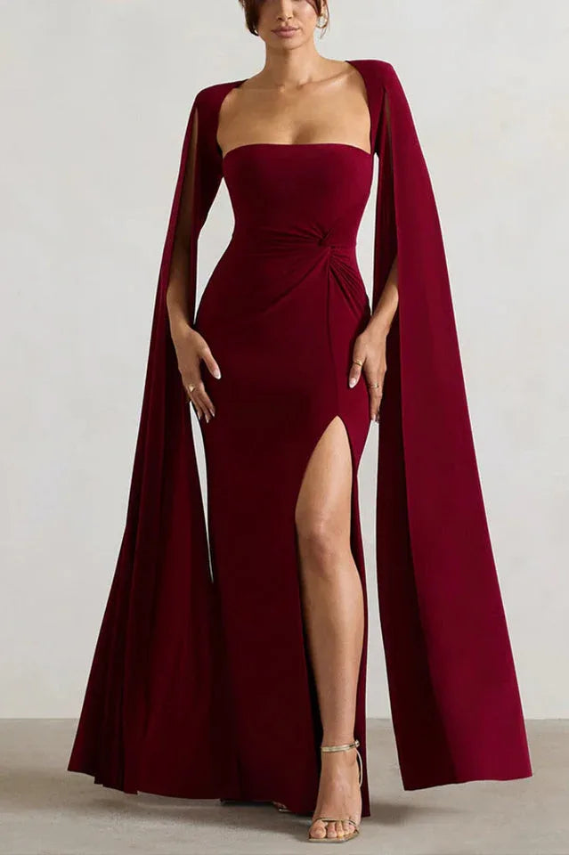Full-length view of a woman in a maroon gown with a sweetheart neckline, draped waist, and flowing cape sleeves.