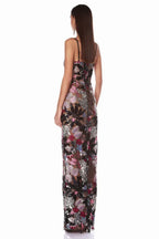 Back view of a woman in a floor-length evening gown with floral embellishments and a sheer construction.
