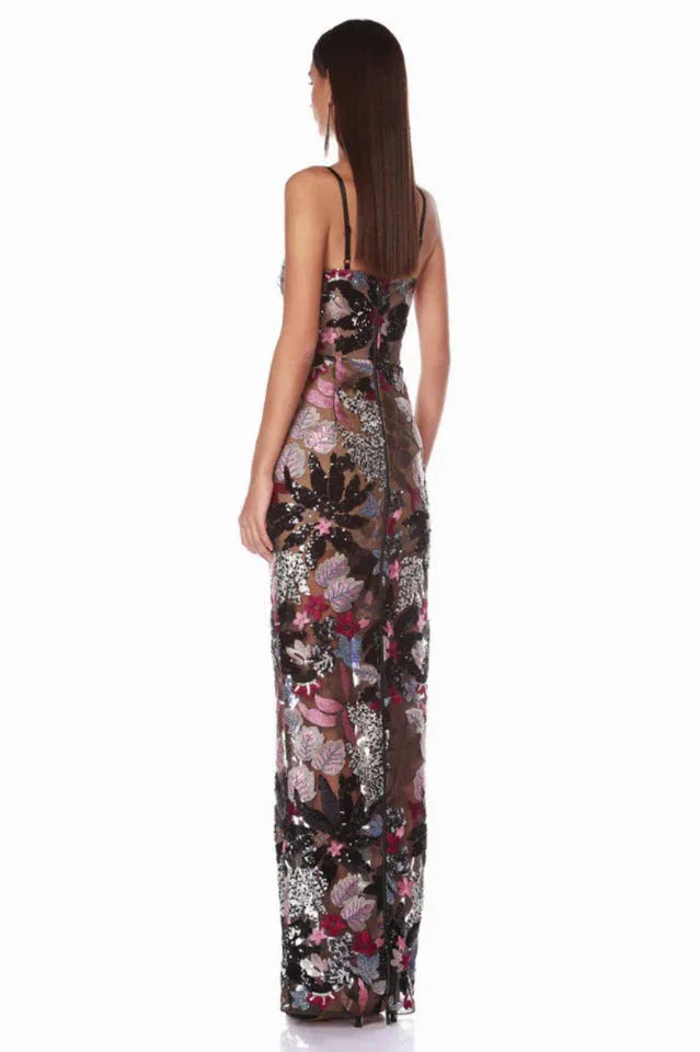 Back view of a woman in a floor-length evening gown with floral embellishments and a sheer construction.