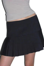 Close-up of a black pleated mini skirt with a textured waistband.