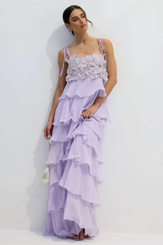 Woman adjusting the skirt of a light purple tiered ruffled chiffon dress with a floral applique bodice.