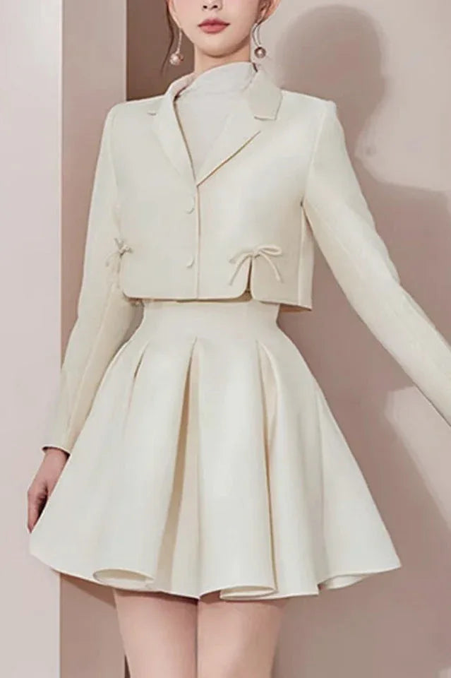 Model wearing a cream-colored cropped jacket and pleated skirt Main image