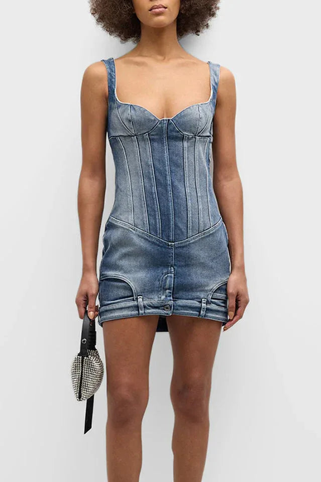 Model wearing a blue denim corset mini dress and holding a silver handbag, viewed from the front.