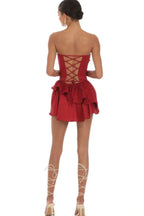 Back view of a woman wearing a red strapless mini dress with a tiered ruffled skirt and lace-up back detail.