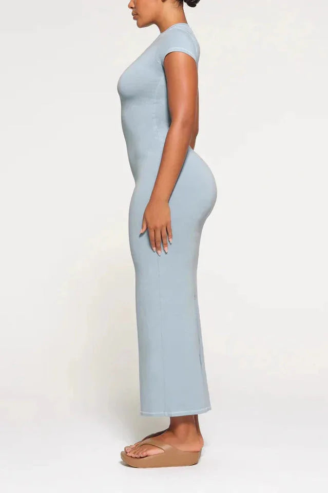 Side view of a woman in a light blue, full-length, fitted knit dress with cap sleeves and a round neckline.