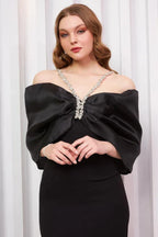 Close-up of the bodice of a black formal dress featuring a large satin bow and crystal detailing