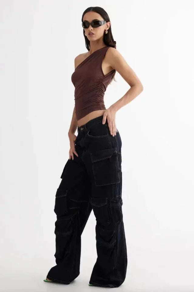 Woman wearing a brown one-shoulder top and dark wash wide-leg cargo pants, side view Secondary image