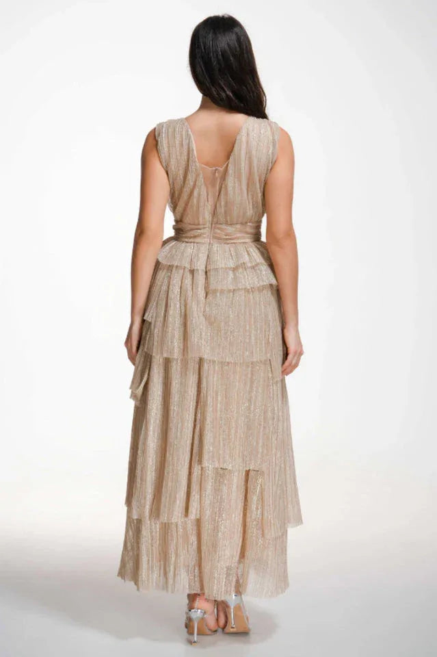 Back view of a woman wearing a champagne-colored sparkly tiered gown with a V-neckline and empire waist.