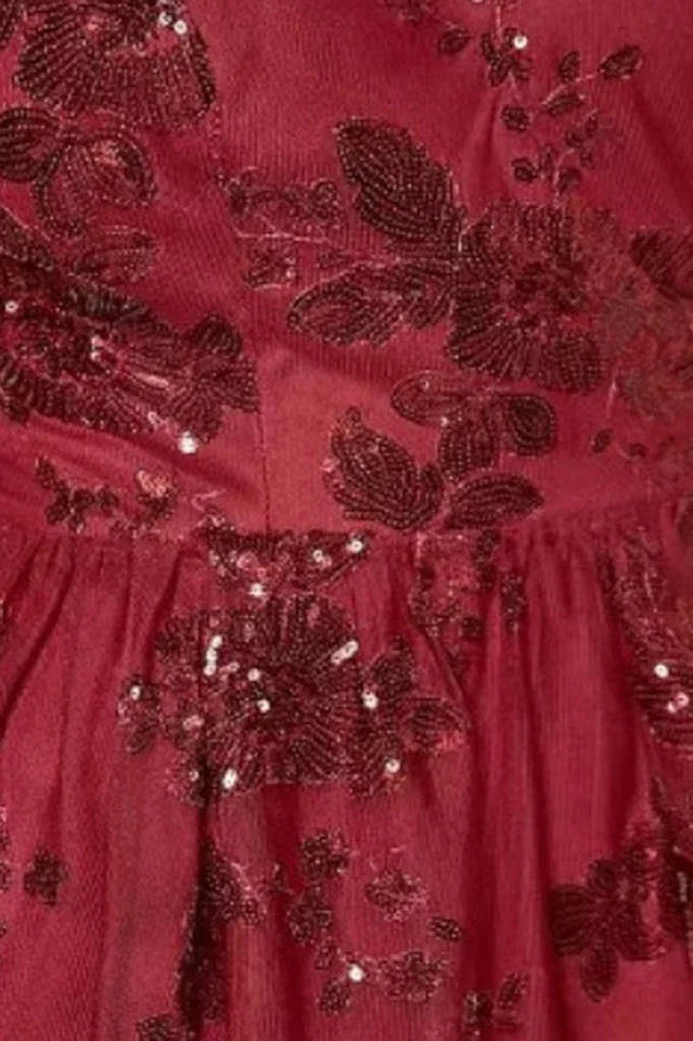 Detail shot of the embroidered floral pattern and sequins on a burgundy dress.