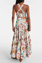 Back view of a woman wearing a white seashell print cropped halter top and a tiered maxi skirt.