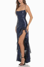 woman wearing a navy blue sequined gown with a high slit and ruffle trim, side view