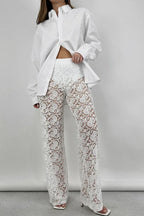 Front view of a woman in a white oversized button-down shirt and white lace wide-leg pants, posing.
