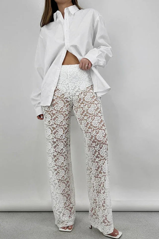 Front view of a woman in a white oversized button-down shirt and white lace wide-leg pants, posing.