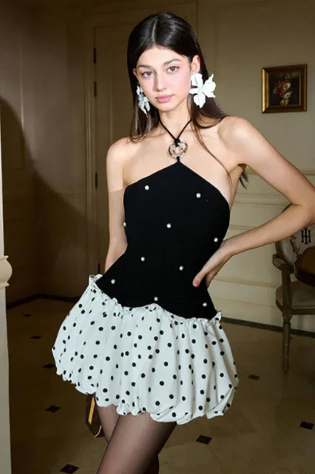 Woman in a black and white polka dot dress with butterfly earrings