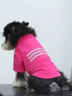Side view of a miniature schnauzer dog wearing a pink t-shirt with text graphic