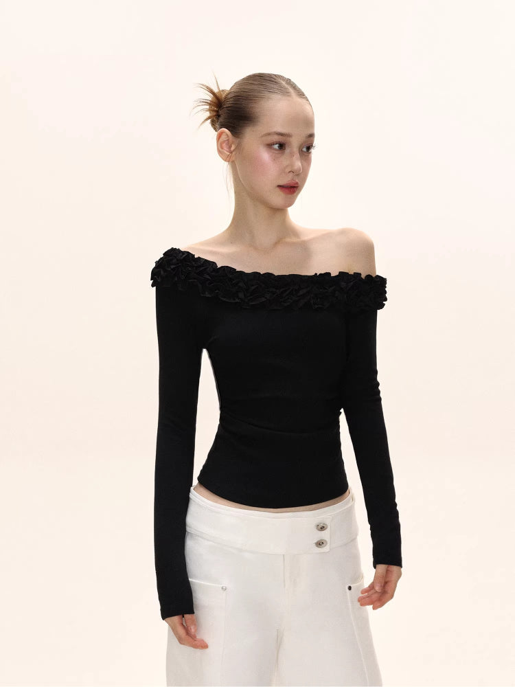 Side view of a model in a black off-the-shoulder long-sleeved top with ruffle detailing, and white wide-leg pants.