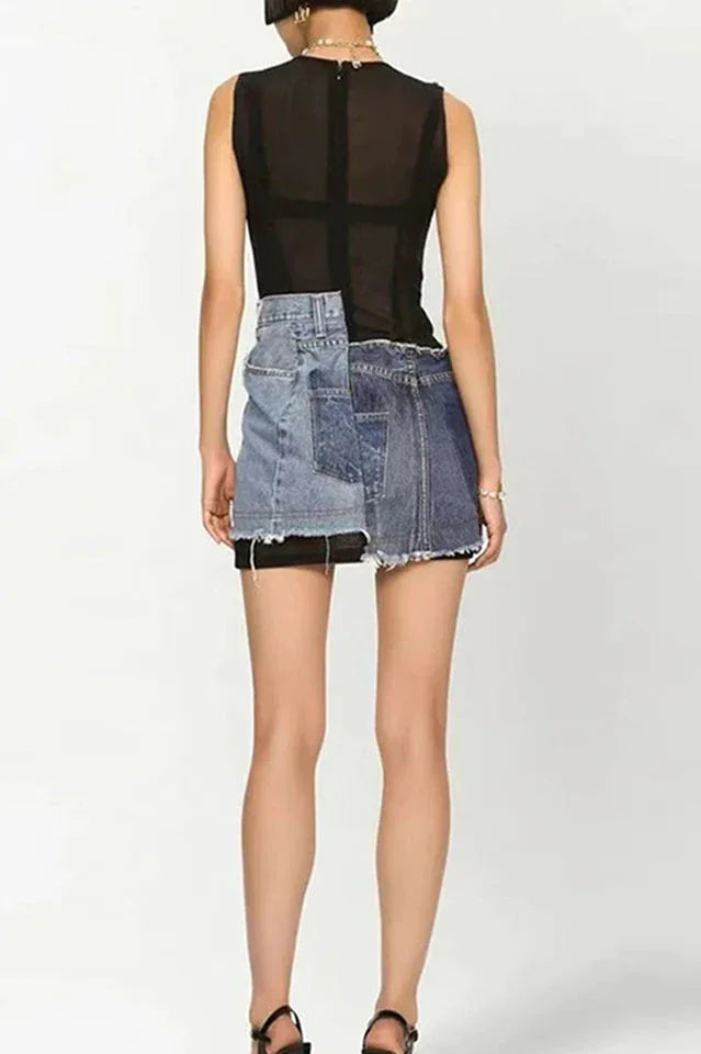 Back view of a model wearing a sleeveless black mesh mini dress with an asymmetrical deconstructed denim overlay