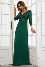 Woman wearing a floor-length emerald green sequined formal gown with 3/4 sleeves, standing in a doorway.