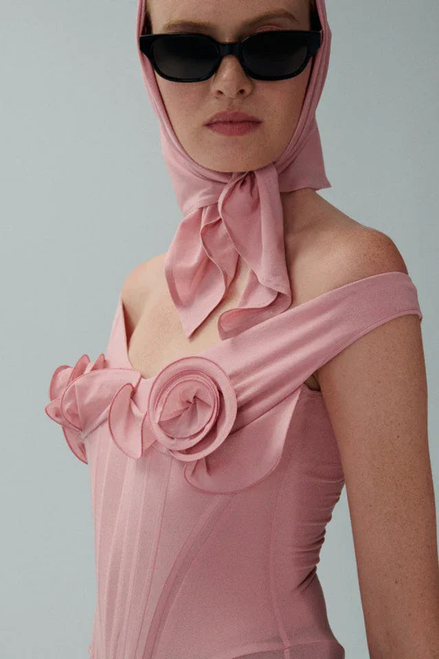 Detail shot of the floral appliqués and ruffled neckline of a pink mesh dress.