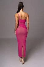 Back view of a woman in a hot pink, one-shoulder, ruched dress with a side slit.