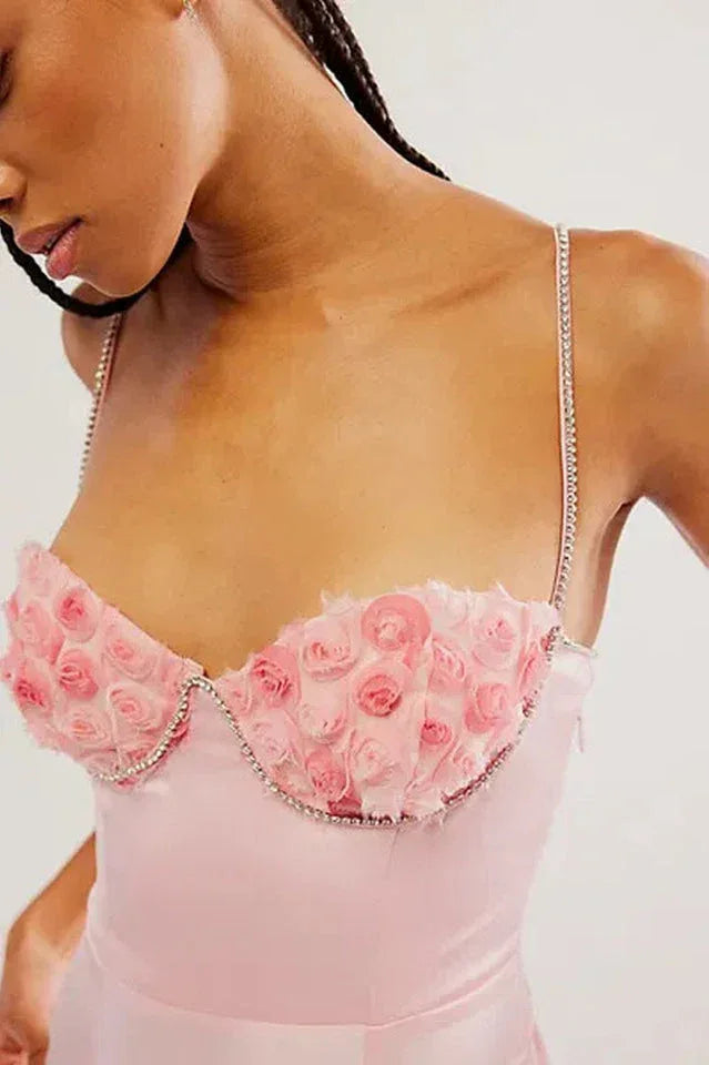 A close-up of the floral applique and beaded trim on the bodice of a pink dress.