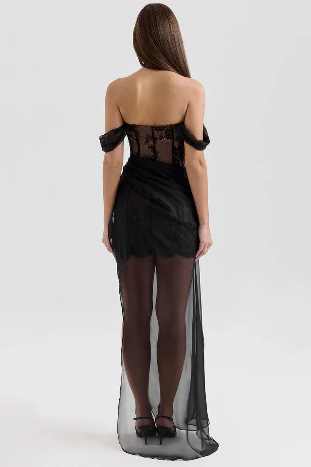 Back view of a woman in a black off-the-shoulder lace corset dress with a sheer flowing skirt