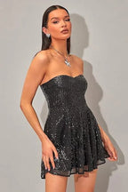 Woman wearing a black sequined strapless dress with a sweetheart neckline and A-line skirt, side-front view