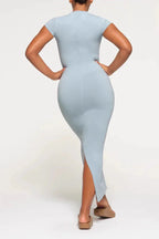 Back view of a woman in a light blue, full-length, fitted knit dress with cap sleeves and a round neckline.