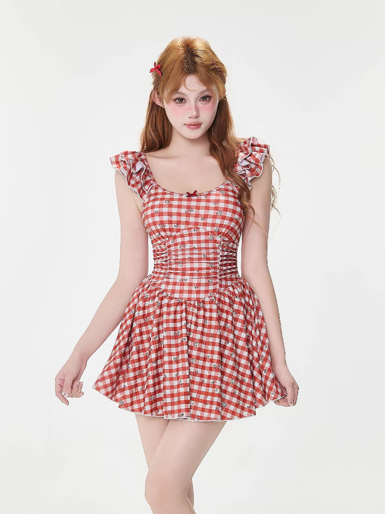 Woman in a red and white gingham dress with ruffled sleeves, cinched waist, and a bow detail on the neckline.