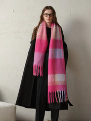 A woman models a cozy, oversized plaid scarf with a fringe detail.