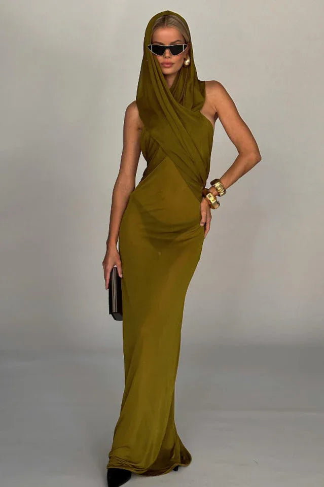 Model wearing a flowing olive green hooded maxi dress with a draped bodice and sheer skirt overlay, accessorized with sunglasses and gold bangles. Main image