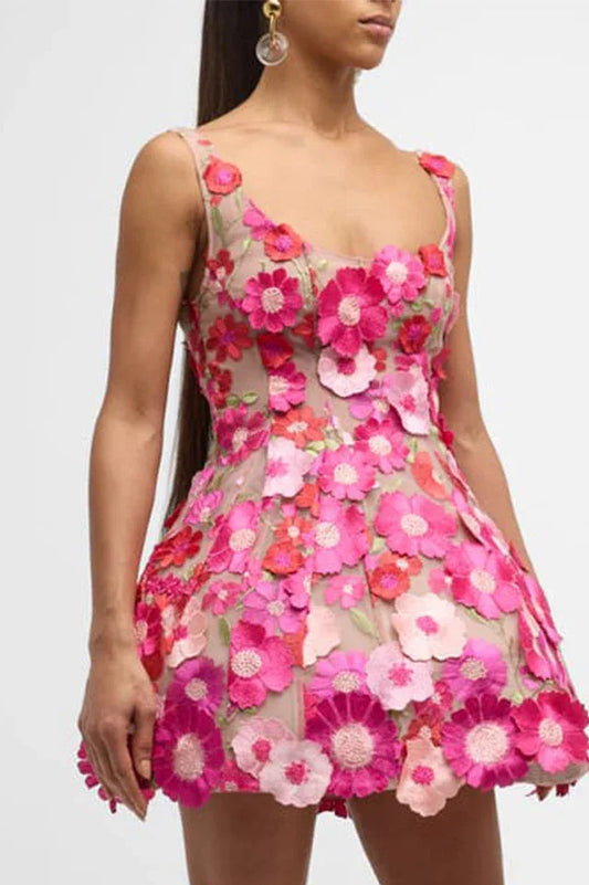Close-up view of a sleeveless mini dress covered in three-dimensional pink and red flowers. The sheer fabric allows the skin to be visible underneath.