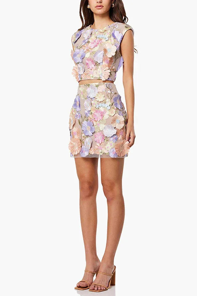 Side view of a woman in a floral applique crop top and mini skirt.