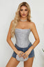 Woman wearing a silver sequined strapless corset top with denim shorts
