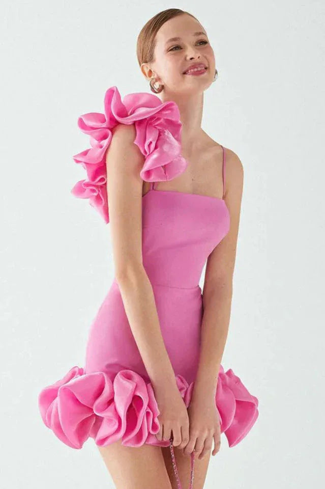 back view of a model in a bright pink mini dress with a large ruffle on one shoulder and a ruffled hem
