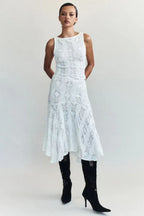 Front view of a woman wearing a white crochet knit cropped tank top and a white crochet knit asymmetrical hem midi skirt with black boots.