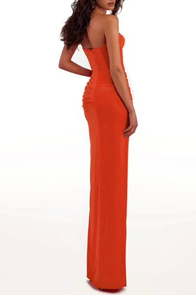 Back view of a woman in a strapless orange ruched gown with a high slit