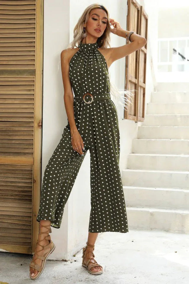 Woman posing in a green polka dot halter neck wide leg jumpsuit with a belt.