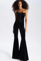 Full body shot of a model in a black velvet corset and flared pants