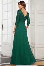Back view of a woman in a floor-length emerald green sequined formal gown with 3/4 sleeves.
