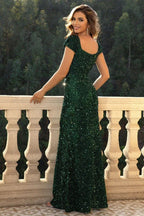 Back view of a woman in a floor-length emerald green sequined mermaid dress with cap sleeves.