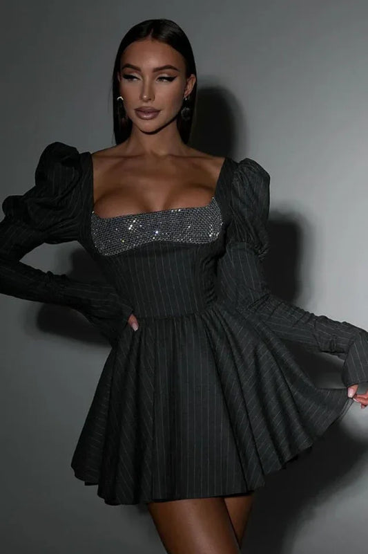 Woman wearing a dark pinstripe mini dress with a sparkling square neckline and dramatic puff sleeves.