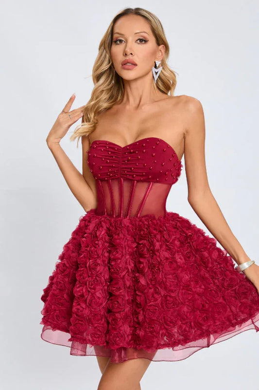 Close-up of a woman in a strapless red dress, highlighting the ruched bodice, beaded details, and sheer corset waist.