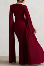 Back view of a woman in a maroon column gown with cape sleeves.