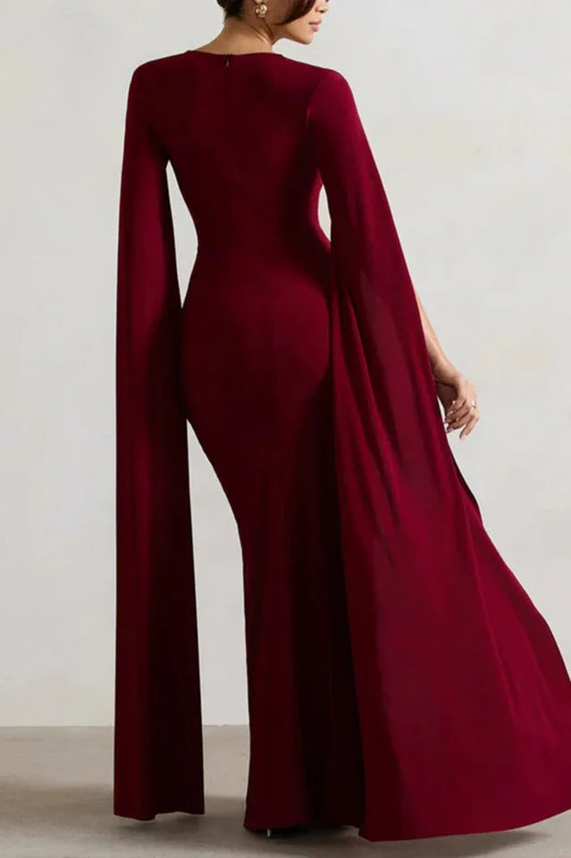 Back view of a woman in a maroon column gown with cape sleeves.