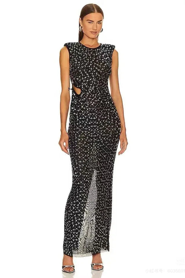 Model wearing a black sleeveless column gown with sequined embellishments and a cut-out detail