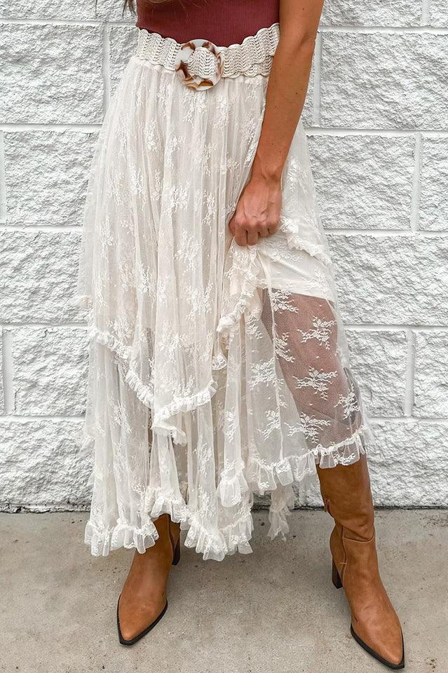 A woman wearing a white lace tiered ruffle skirt with brown boots and a brown belt. Main image