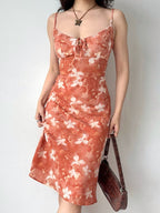 Woman posing with hands on hips, wearing a floral print midi slip dress.